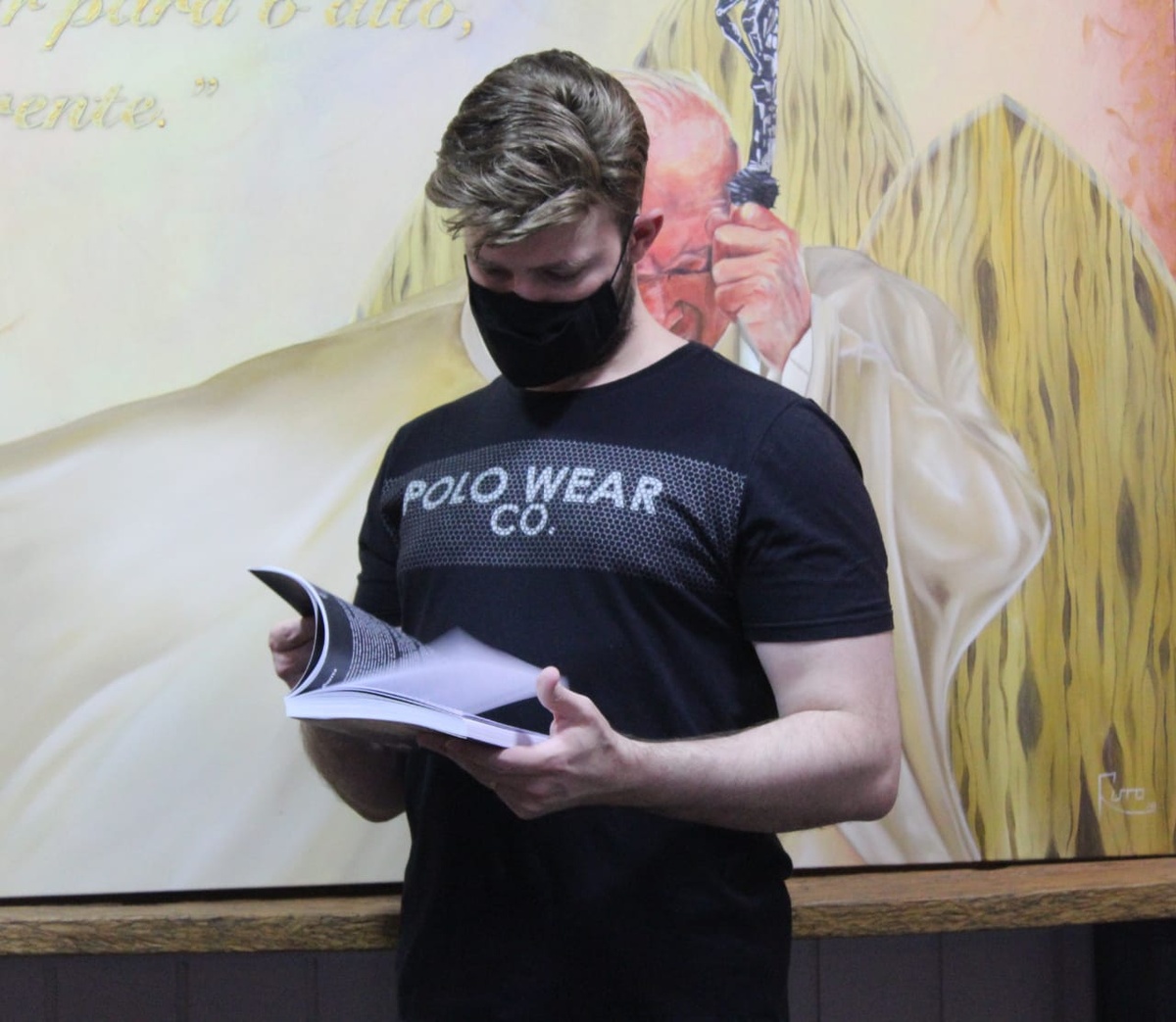 A guest reading Malakoi – Desviado in front of the John Paul II painting